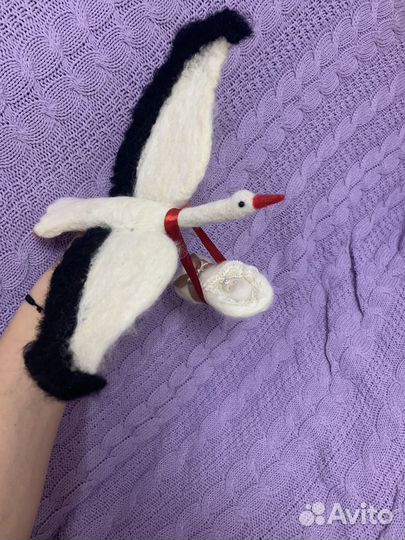 Аист с младенцем на красной ленте